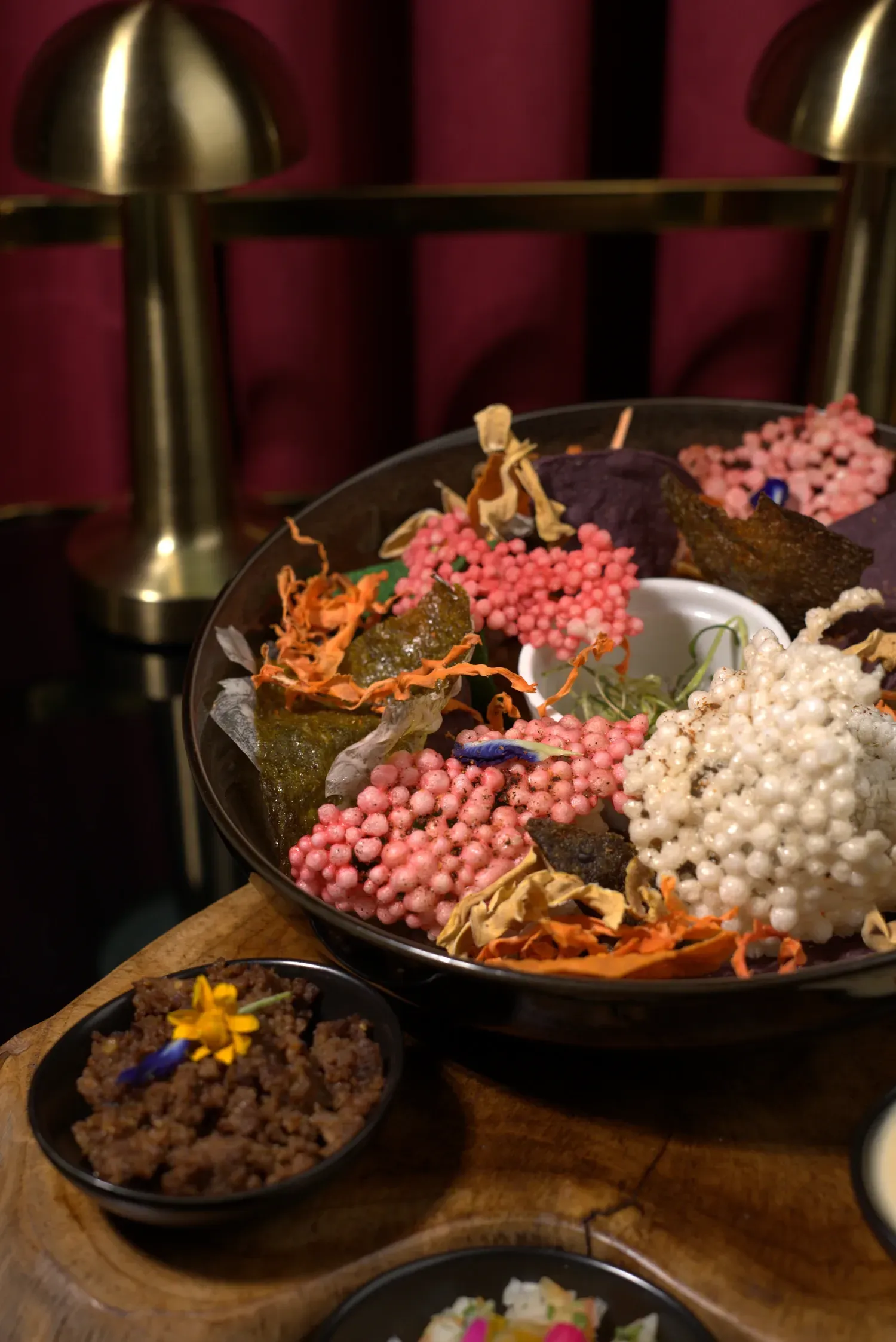 Appetizer platter with colorful toppings, small brown bowl with food in the foreground.