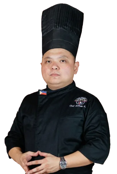 Chef in black uniform and hat, arms crossed, with Philippine flag patch.