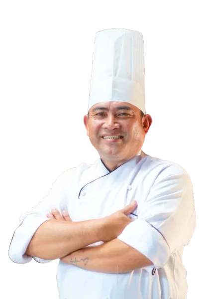 Chef in white uniform and hat, arms crossed, smiling.